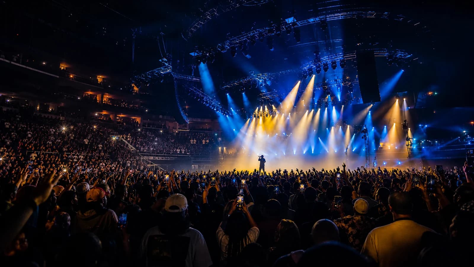 Wide view of a high-energy hip-hop arena concert under blue and amber lights