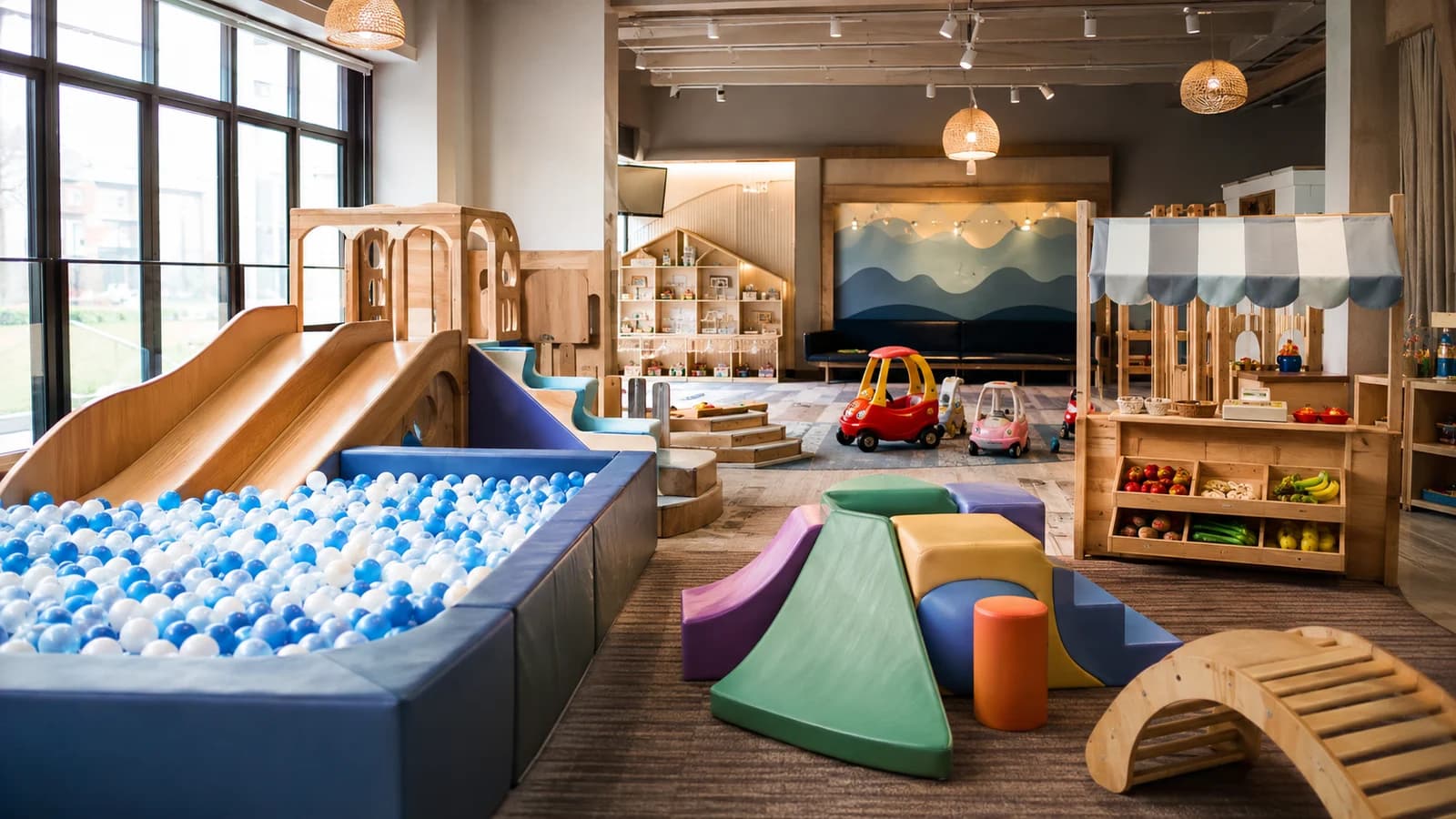 Bright indoor play center with ball pit, slides, foam climbers, pretend market, and ride-on toys