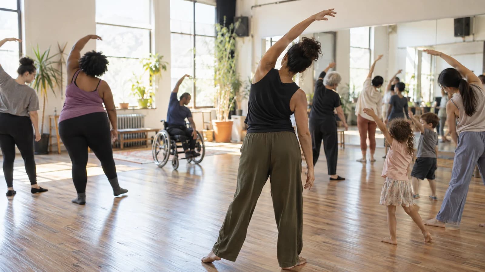 Original editorial scene of an inclusive mixed-age movement class in a sunny Brooklyn community studio