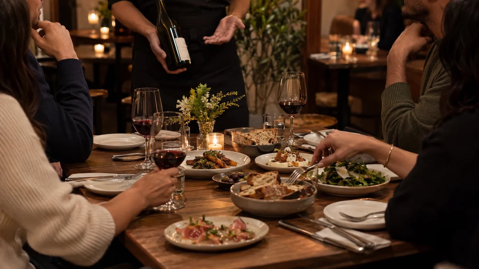 Original editorial scene of friends planning shared plates and wine in an intimate Williamsburg dining room