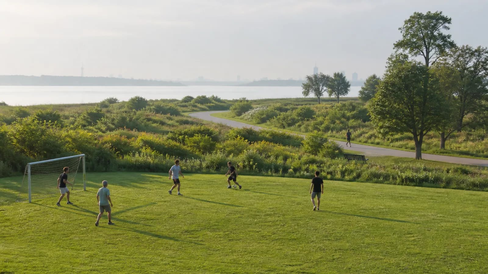 Athletic lawn, coastal vegetation, and walking path at Canarsie Park near Jamaica Bay